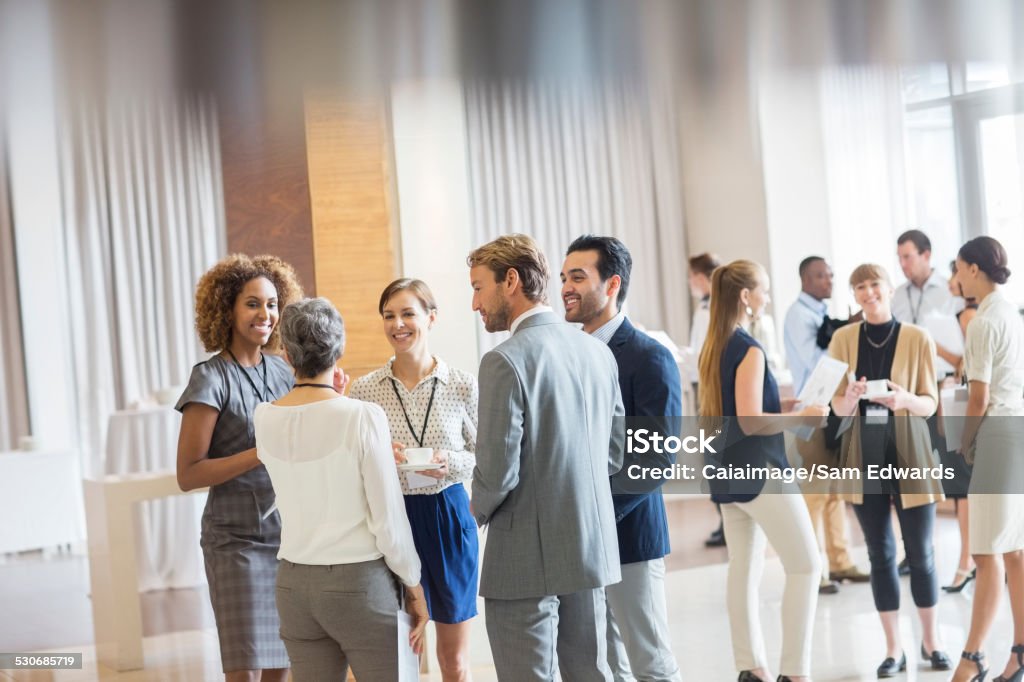 Group of business people standing in hall, smiling and talking together  Meeting Stock Photo