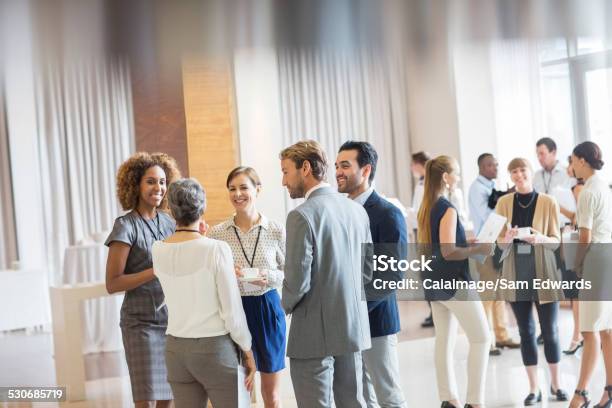 Group Of Business People Standing In Hall Smiling And Talking Together Stock Photo - Download Image Now