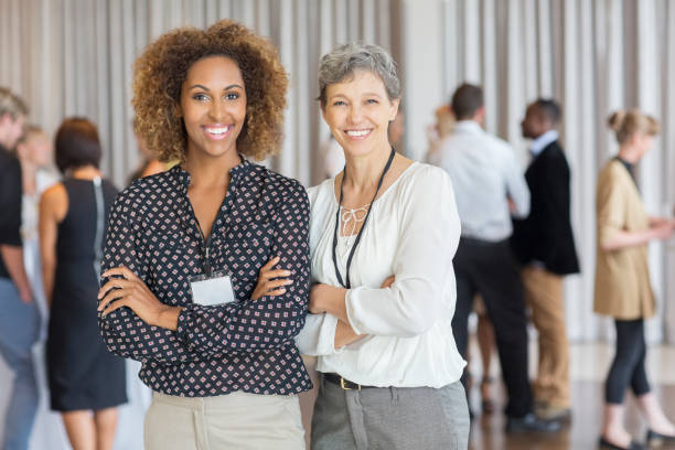 femmes d’affaires posant devant des collègues au bureau - personne secondaire photos et images de collection