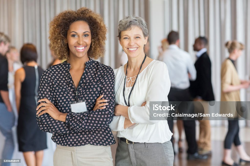 Businesswomen posing in front of colleagues in office  Connection Stock Photo
