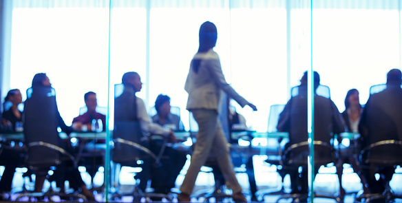 istock Businesswoman walking in front of colleagues during business meeting in conference room 530685889