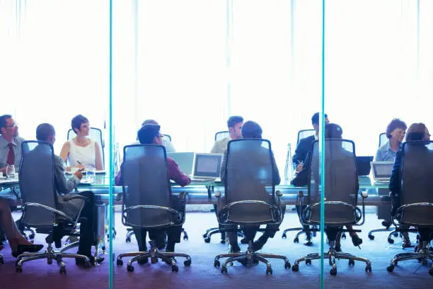 Photo of Business people having meeting in conference room, sitting with laptops and discussing