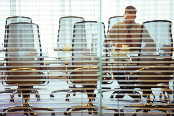 istock Businessman sitting behind blinds in conference room 530685897