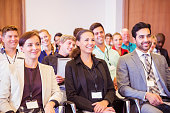 Business people sitting in conference room, smiling and looking away