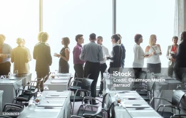 Group Of People Standing By Windows Of Conference Room Socializing During Coffee Break Stock Photo - Download Image Now