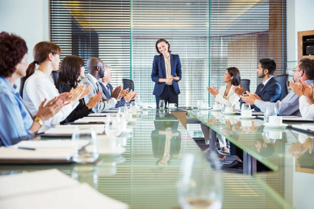 participantes da conferência aplaudindo jovem empresária em pé na mesa de conferência - coffee board room office meeting - fotografias e filmes do acervo