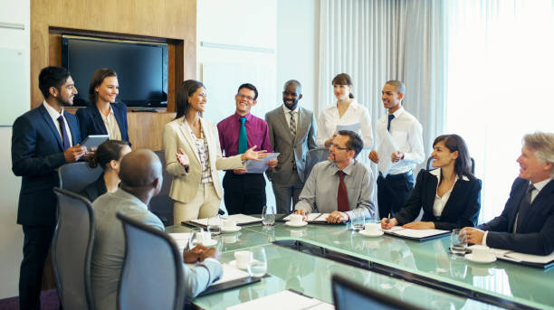 bizneswoman stojąca na czele stołu konferencyjnego i rozmawiająca - coffee board room office meeting zdjęcia i obrazy z banku zdjęć