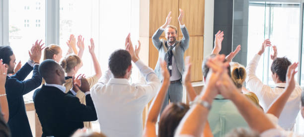 Portrait of smiling man standing before audience in conference room, applauding  women satisfaction decisions cheerful stock pictures, royalty-free photos & images