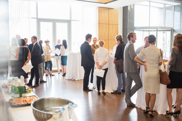 group of conference participants standing in lobby of conference center, socializing during lunch break - parties imagens e fotografias de stock