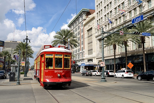 New Orleans, Louisiana, USA - October 28, 2014: A bright red Streetcar running on Canal Street at the intersection with Dauphine Street. The Canal Streetcar line is the part of New Orleans historic street railway system since 1861. It was shut down and replaced by bus service in 1964. Then in 2004, 40 years after its close, the Streetcar service was restored to Canal Street. The Canal line running along the New Orleans' 