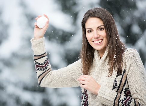 Beautiful natural woman with stunning eyes and a perfect candid smile throwing a snowball at the viewer. 