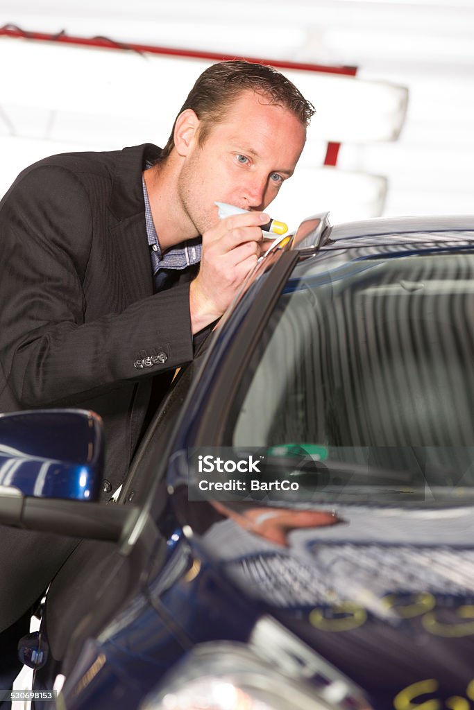 Adult appraiser looking at car, estimate for fix An insurance expert examining case of damage at car. Car Insurance, appraiser. Vertical indoor picture Appraiser Stock Photo