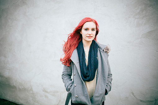 portrait of a young redhead female in front of a concrete wall