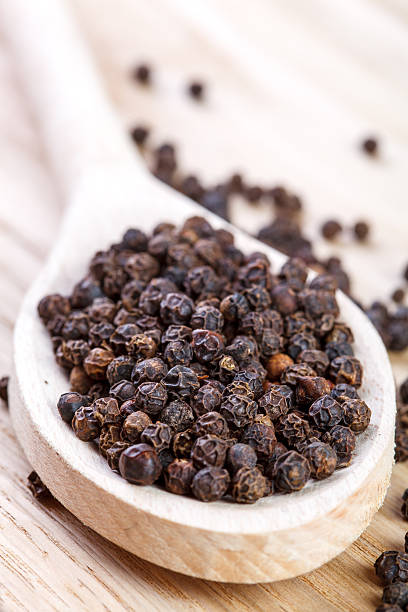 istock Black pepper on wooden spoon close up 530703727