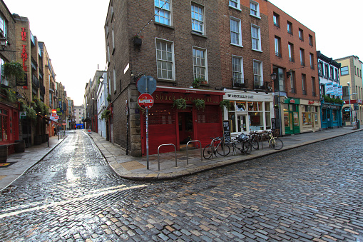 A cobbled intersection with shops, pubs, restaurants, and bikes in the Temple Bar area, Dublin, Ireland. Shot in early morning. Copy space on the cobbles.
