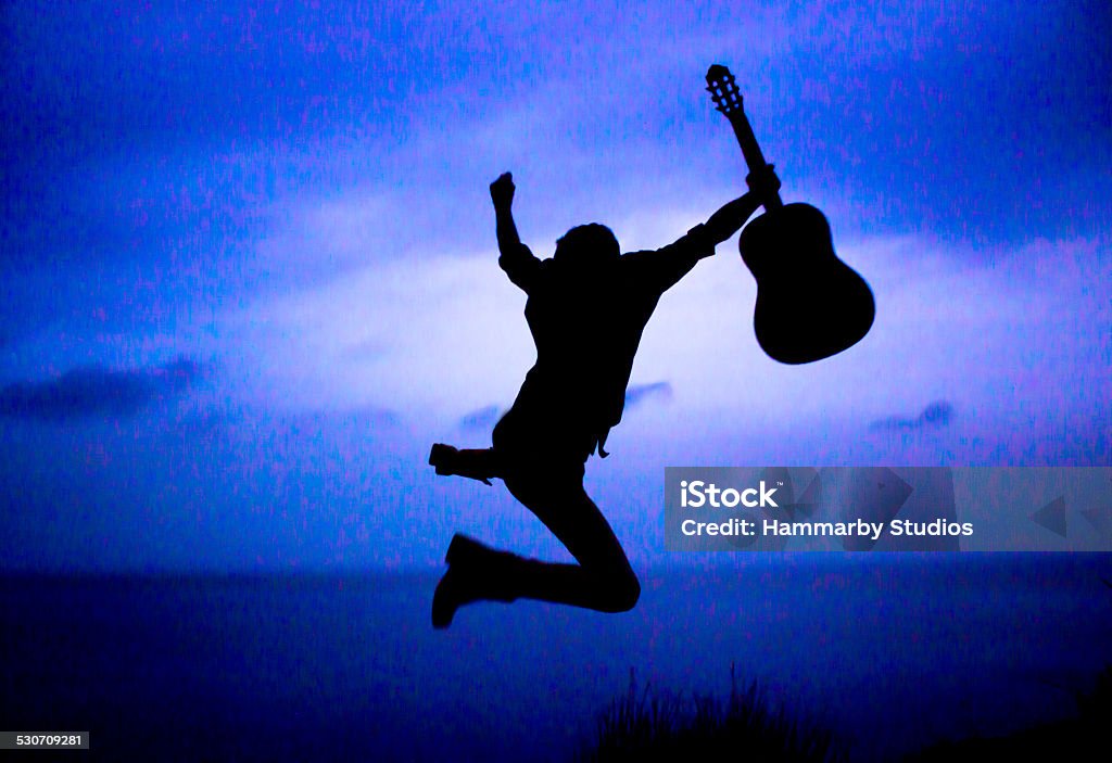 Young man with guitar Young man who holding guitar jumping Beach Stock Photo