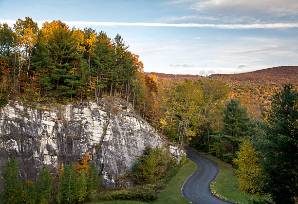 Road through thick fall foliage and marble rock formation