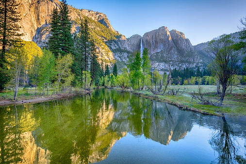 Wide angle view of early morning sunlight at Yosemite Falls, reflected in the Merced River. Yosemite National Park, California, USA.
