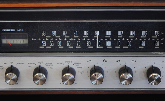 Front-facing shot of a vintage AM / FM Receiver with rotary dials.