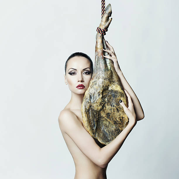 Nude elegant woman with Iberian jamon stock photo