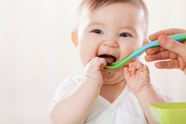 Feeding Mother feeding her baby. baby food stock pictures, royalty-free photos & images