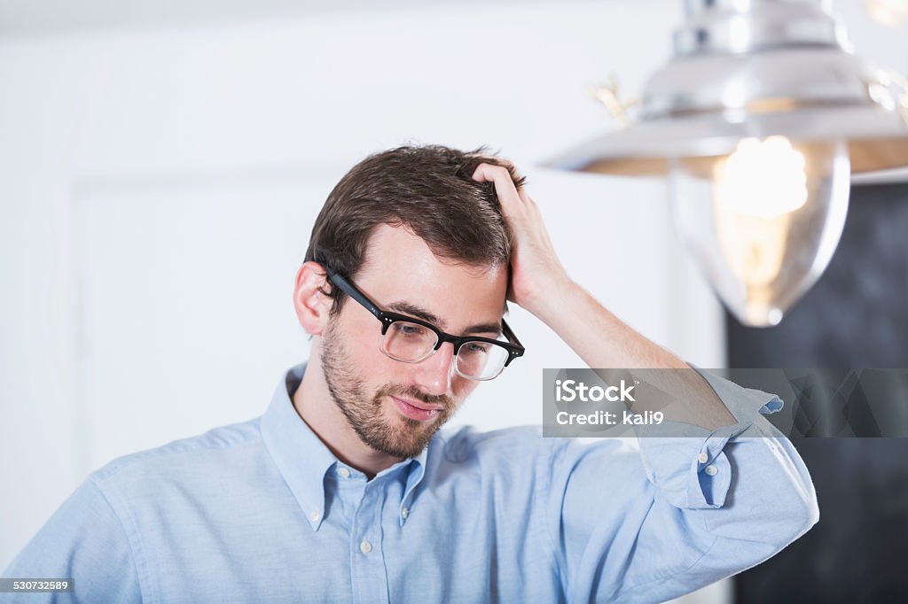 Young man scratching head Young man wearing eyeglasses, scratching his head. 20-24 Years Stock Photo