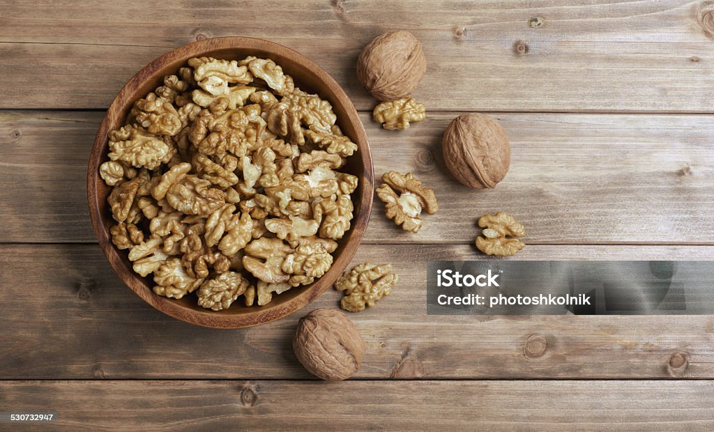 Walnuts in wooden bowl Walnuts in wooden bowl on wooden table Walnut Stock Photo
