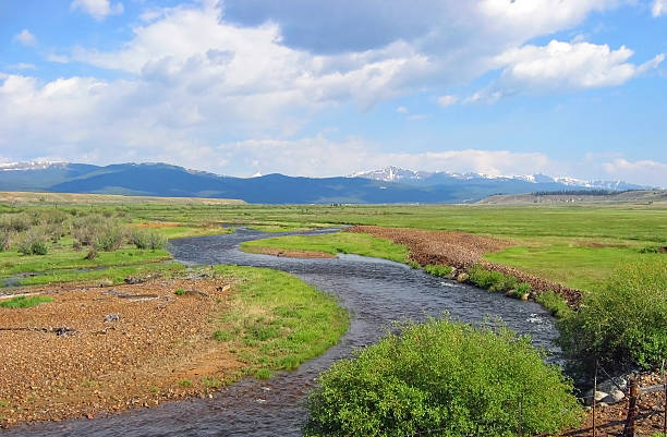 Mountain River Tranquil river flowing through plains with snow capped mountains in the background. Headwaters of the Arkansas river in Rocky Mountains near the Leadville area of Colorado. leadville stock pictures, royalty-free photos & images