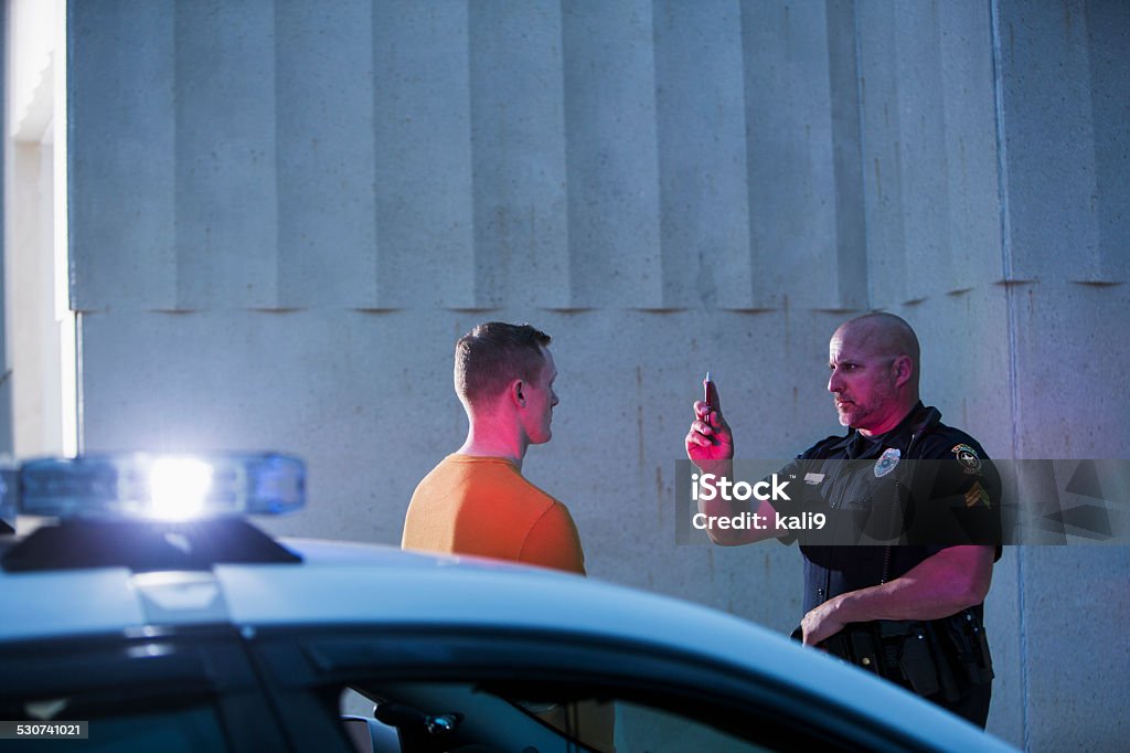 Policeman performing sobriety test on driver Police officer giving sobriety test to young man to see if he is driving under the influence of drugs or alcohol.  Top of the police cruiser is out of focus in the foreground. Drunk Driving Stock Photo