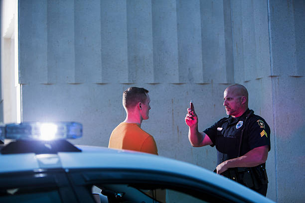 Policeman performing sobriety test on driver Police officer giving sobriety test to young man to see if he is driving under the influence of drugs or alcohol.  Top of the police cruiser is out of focus in the foreground. driving under the influence stock pictures, royalty-free photos & images
