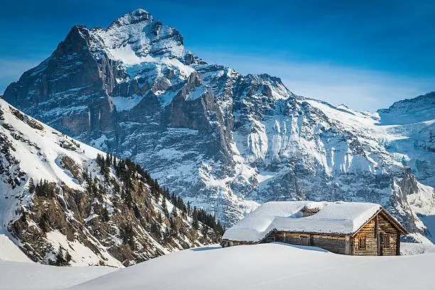 Traditional wooden cabin covered in deep snow high in the idyllic winter mountain wilderness of the Alps, Switzerland. ProPhoto RGB profile for maximum color fidelity and gamut.