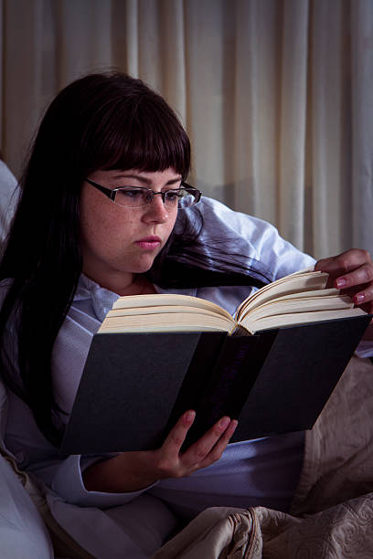 istock Young Woman Relaxing And Reading A Book In Bed 530743021