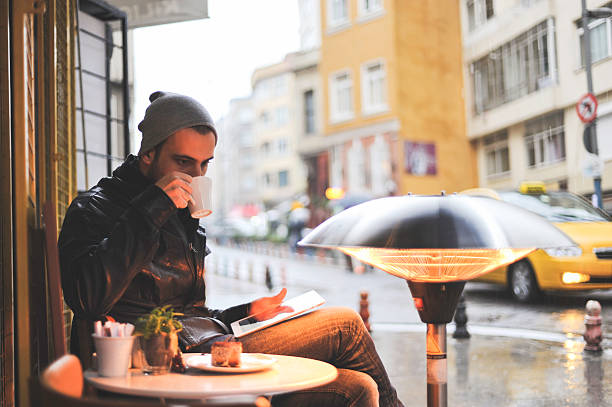 Young Man drinking coffee looking at his digital tablet stock photo