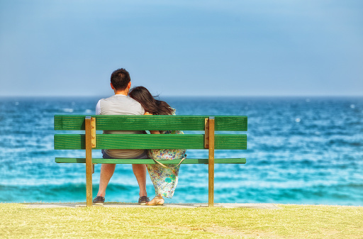 Palm Beach,Australia - January 1, 2015: A couple cuddling as they enjoy the view out to sea on a warm summer's day.