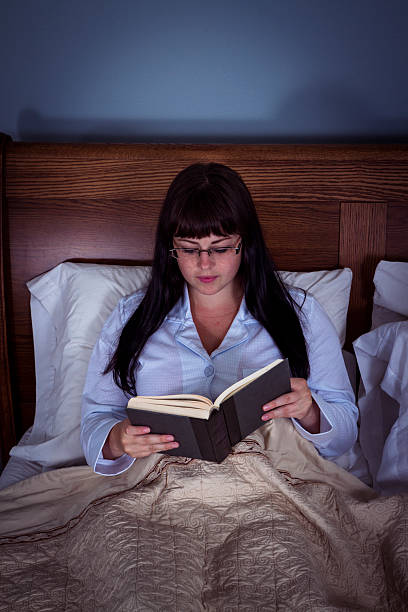 istock Young Woman Relaxing And Reading A Book In Bed 530745181