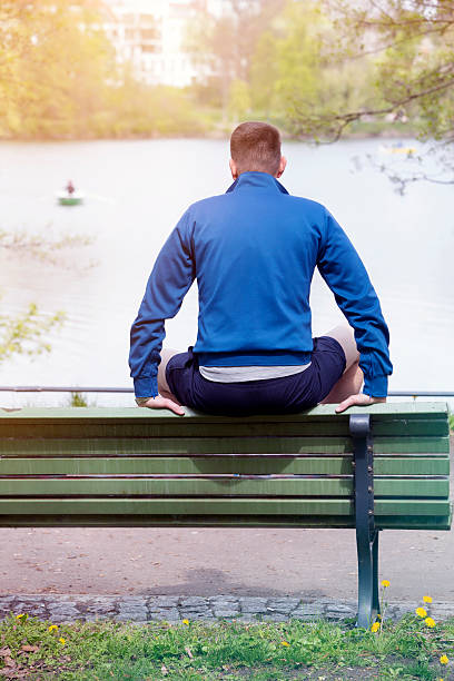 istock man sitting on bench and looking at a lake 530745248