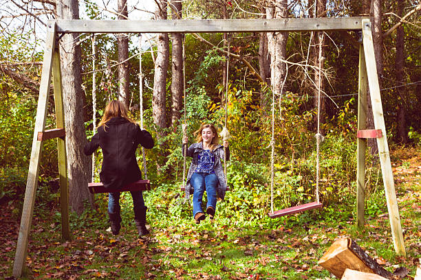 istock Teens Swinging On An Old Swing Set In The Yard 530746153