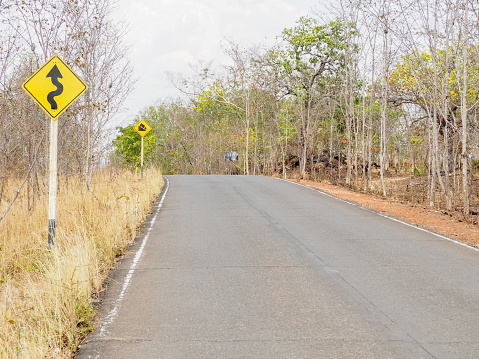 winding road left ahead sign and Hill symbol on country road