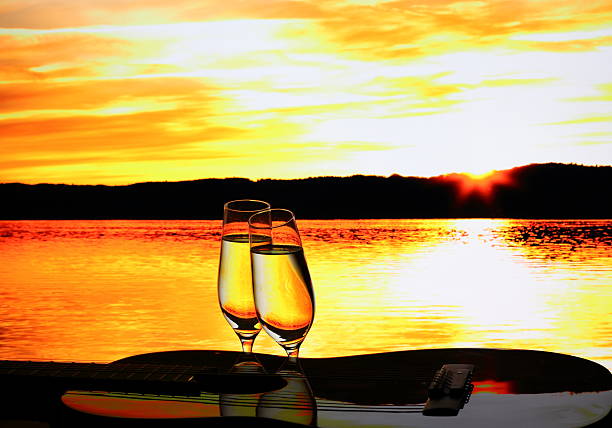 Two champagne glasses with guitar at sunset, close up
