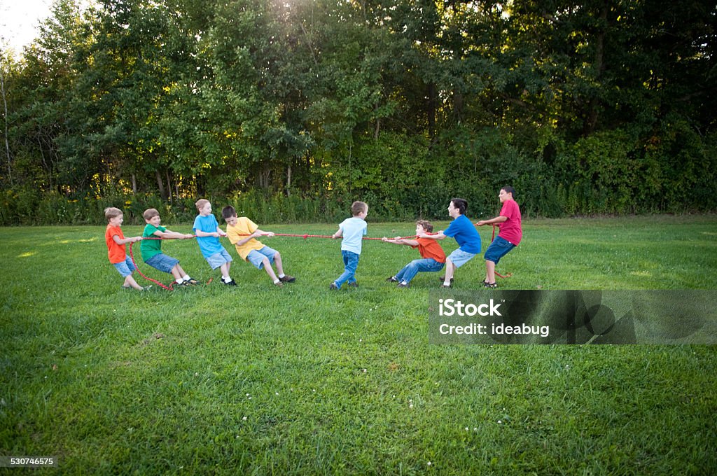 Group of Boys Playing Tug-of-War Competition Outside Color photo of a group of boys playing a tug-of-war competition outside on a beautiful summer day. Child Stock Photo