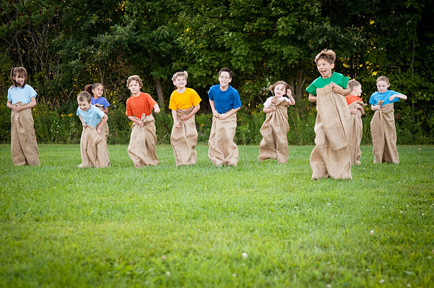 group of happy children having картофель бег в мешках за - child playing sack race sports race стоковые фото и изображения