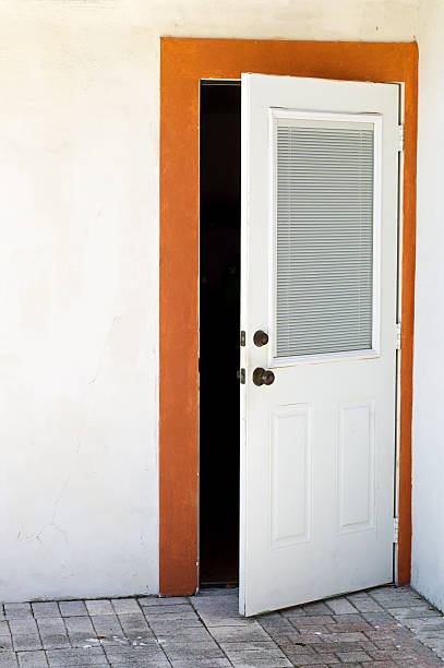 open house door exterior A white residential door is open with large window and framed in orange trim on white wall. ajar stock pictures, royalty-free photos & images