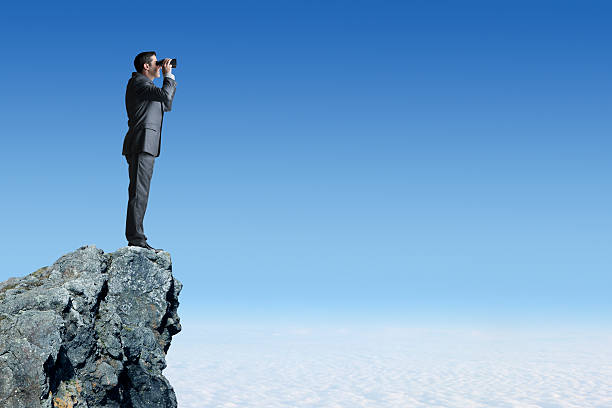 istock Businessman On Top Of Cliff Looking Through Binoculars 530754506