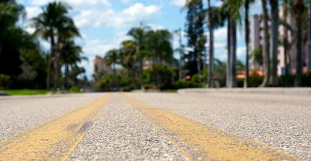 low angle view of road Ground level view of road between yellow lines, shallow depth of field. collier county stock pictures, royalty-free photos & images