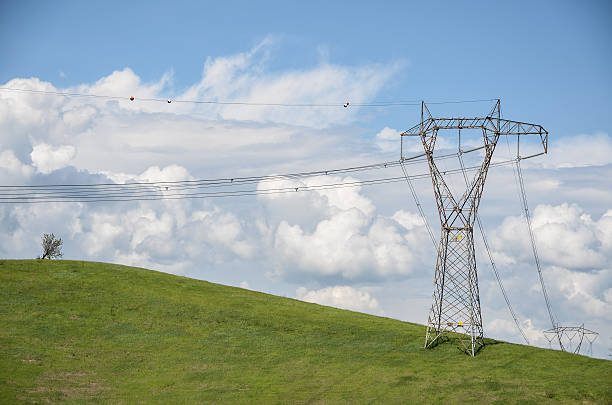 istock power lines on a green hill under cloudy blue sky 530757183