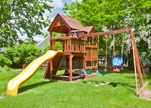 Back Yard Wooden Swing Set on Green Lawn