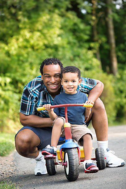 istock African American Father and Young Son outdoors Riding tricycle 530764294