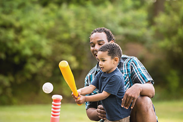 African American Father and Young Son outdoors playing T Ball stock photo