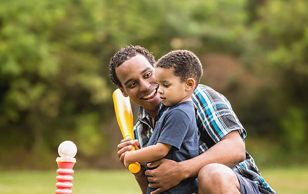 istock African American Father and Young Son outdoors playing T Ball 530766368