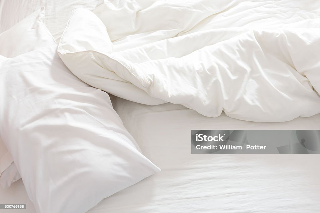 Top view of an unmade bed with crumpled bed sheet. Top view of an unmade bed with crumpled bed sheet, a blanket and pillows after waking up in the morning. Bed - Furniture Stock Photo